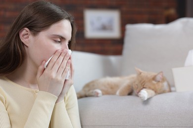 Photo of Woman suffering from allergy with her cat at home, selective focus