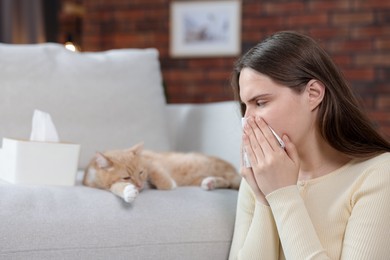 Photo of Woman suffering from allergy with her cat at home, selective focus