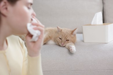 Photo of Woman suffering from allergy with her cat at home, selective focus