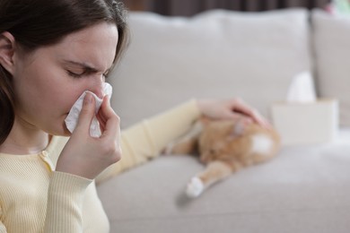 Photo of Woman suffering from allergy with her cat at home, selective focus