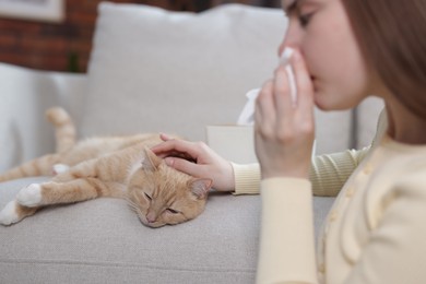Photo of Woman suffering from allergy with her cat at home, selective focus