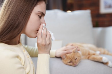 Photo of Woman suffering from allergy with her cat at home, selective focus