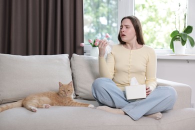 Photo of Woman suffering from allergy with her cat on sofa at home