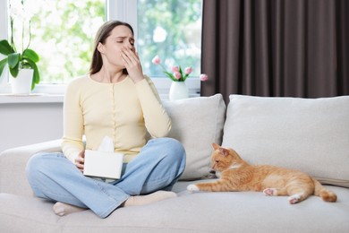 Photo of Woman suffering from allergy with her cat on sofa at home