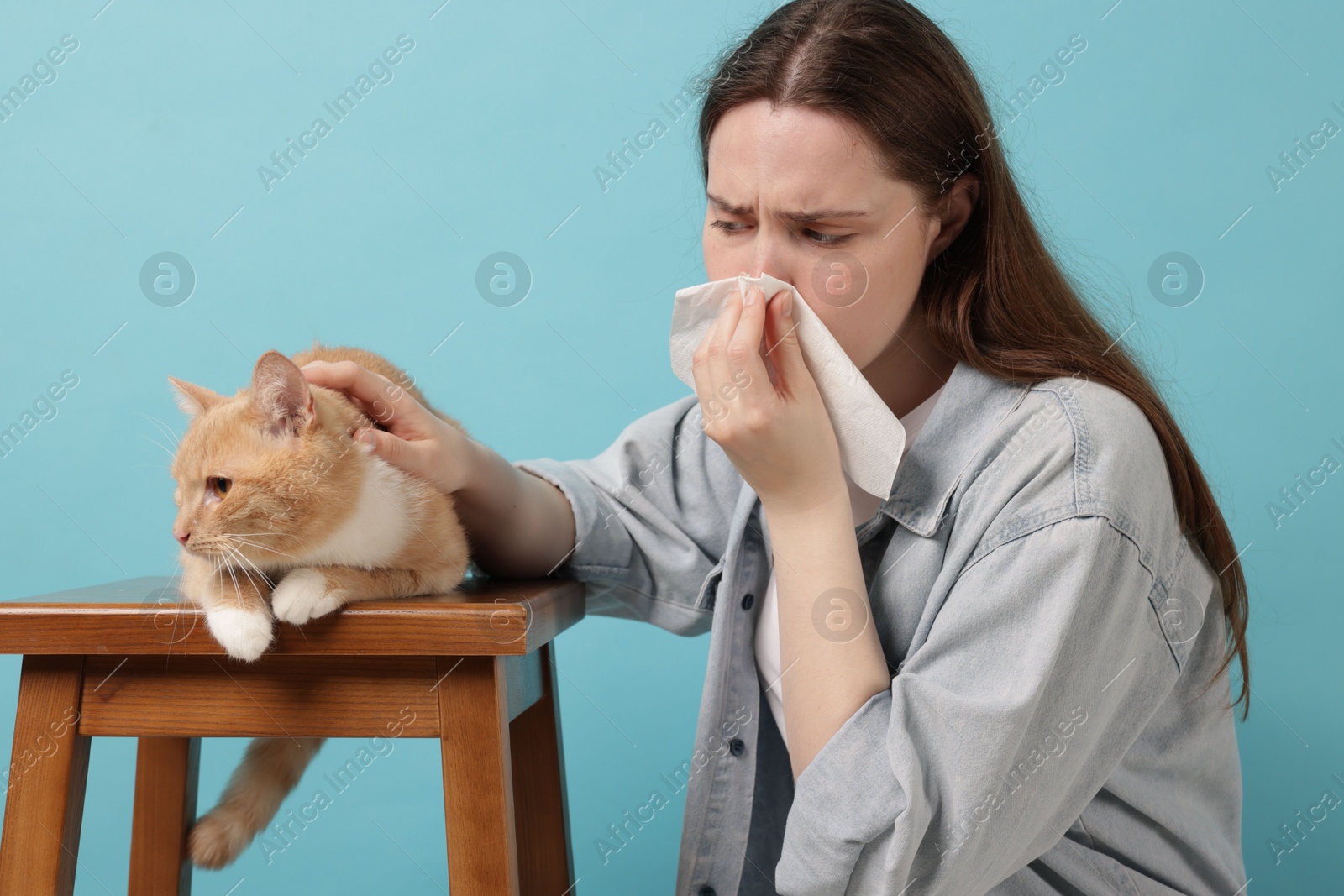 Woman suffering from allergy with her cat on light blue background Photo of Woman suffering from allergy with her cat on light blue background