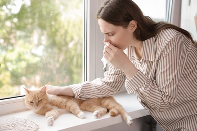 Photo of Woman suffering from allergy with her cat near window at home