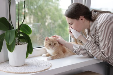 Photo of Woman suffering from allergy with her cat near window at home