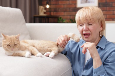 Photo of Senior woman suffering from allergy with her cat at home