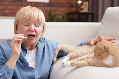 Photo of Senior woman suffering from allergy with her cat at home