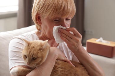 Photo of Senior woman suffering from allergy with her cat on sofa at home