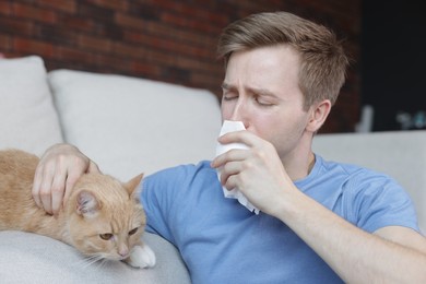 Photo of Man suffering from allergy with his cat at home