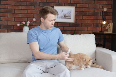 Photo of Man suffering from allergy with his cat on sofa at home