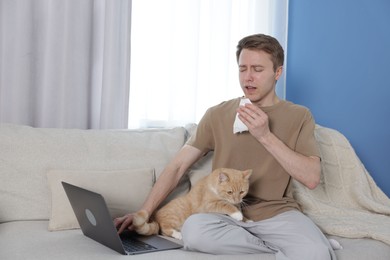 Photo of Man suffering from allergy with his cat on sofa at home