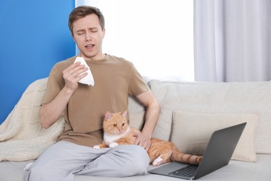 Photo of Man suffering from allergy with his cat on sofa at home