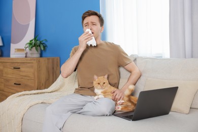 Photo of Man suffering from allergy with his cat on sofa at home