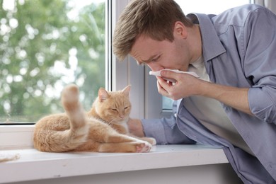 Photo of Man suffering from allergy with his cat near window at home