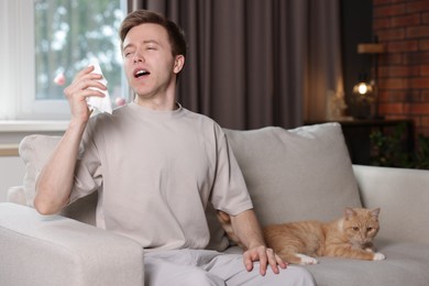 Photo of Man suffering from allergy with his cat on sofa at home