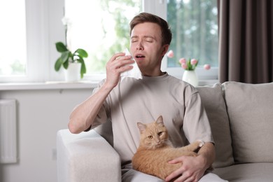 Photo of Man suffering from allergy with his cat on sofa at home