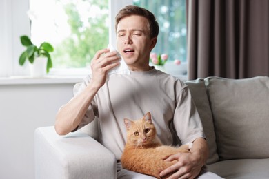 Photo of Man suffering from allergy with his cat on sofa at home