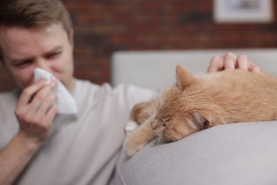 Photo of Man suffering from allergy with his cat at home, selective focus