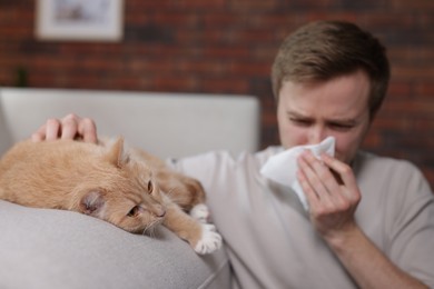 Photo of Man suffering from allergy with his cat at home, selective focus