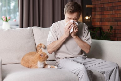 Photo of Man suffering from allergy with his cat on sofa at home