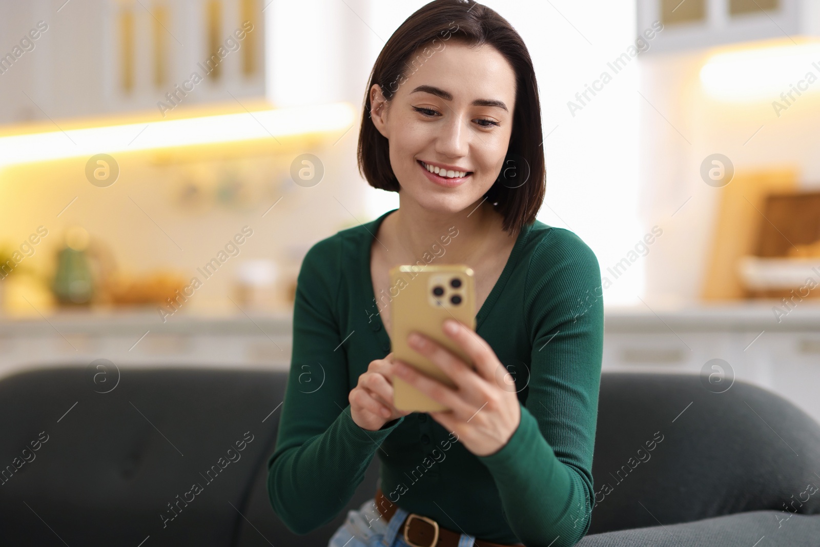 Woman using modern smartphone on sofa at home Photo of Woman using modern smartphone on sofa at home