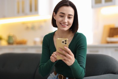 Photo of Woman using modern smartphone on sofa at home