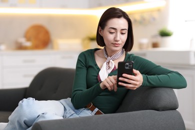 Photo of Woman using modern smartphone on sofa at home. Space for text