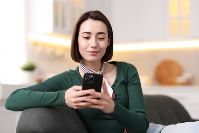 Photo of Woman using modern smartphone on sofa at home