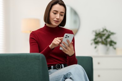 Photo of Woman using modern smartphone on sofa at home