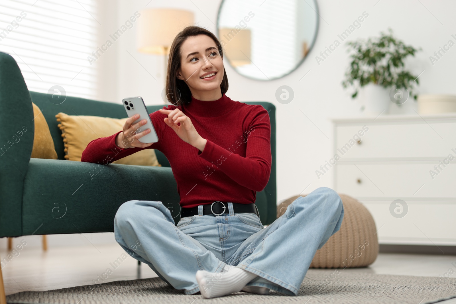 Woman using modern smartphone on floor at home Photo of Woman using modern smartphone on floor at home