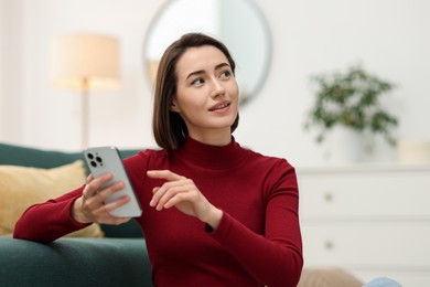 Photo of Beautiful woman using modern smartphone at home