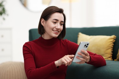 Photo of Beautiful woman using modern smartphone at home
