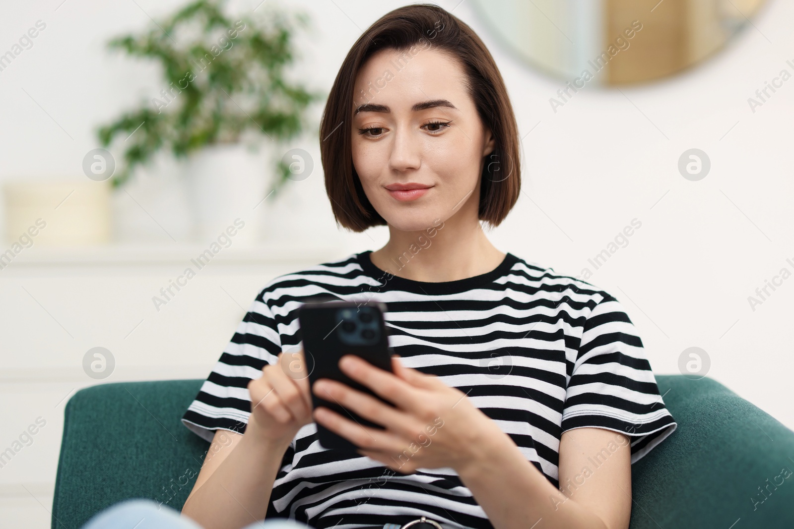 Woman using modern smartphone on sofa at home Photo of Woman using modern smartphone on sofa at home