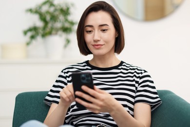 Photo of Woman using modern smartphone on sofa at home