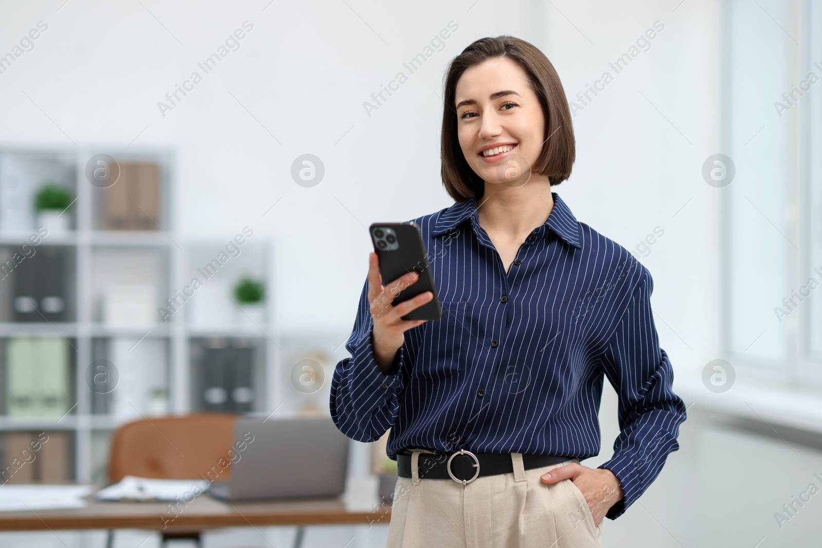 Beautiful woman using her smartphone in office. Space for text Photo of Beautiful woman using her smartphone in office. Space for text