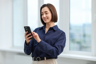 Photo of Beautiful woman using her smartphone in office