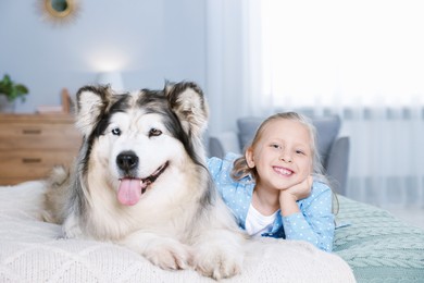 Photo of Little girl and cute dog on bed at home