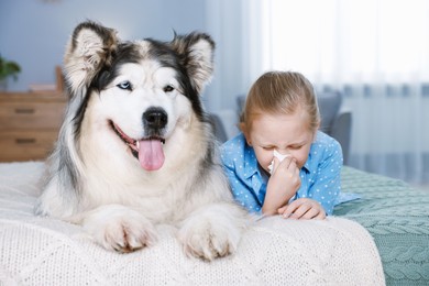 Photo of Girl suffering from allergy with her dog on bed at home