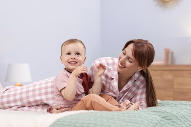 Photo of Happy mother spending time together with her son on bed at home