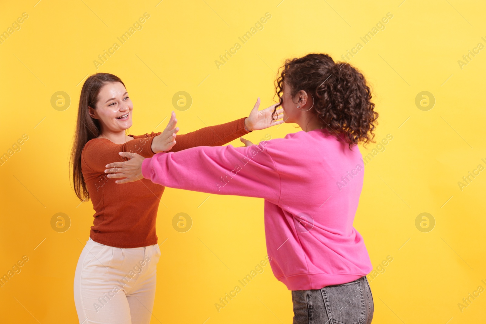 Friends welcoming each other on orange background Photo of Friends welcoming each other on orange background