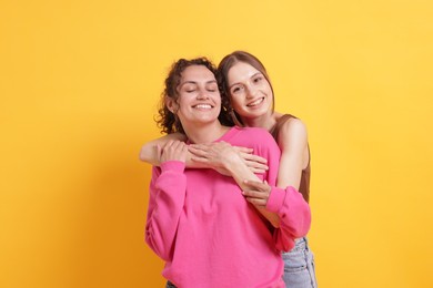 Photo of Friends hugging each other on orange background