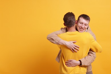 Photo of Friends hugging each other on orange background, space for text