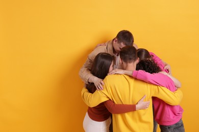 Photo of Group of friends hugging each other on orange background, space for text