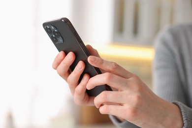 Photo of Woman using modern smartphone at home, closeup