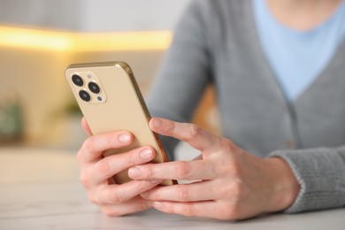 Photo of Woman using smartphone at table indoors, closeup