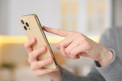 Photo of Woman using modern smartphone at home, closeup