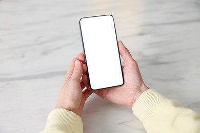 Photo of Woman using modern smartphone at white marble table, closeup