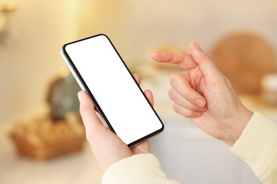 Photo of Woman using modern smartphone at home, closeup